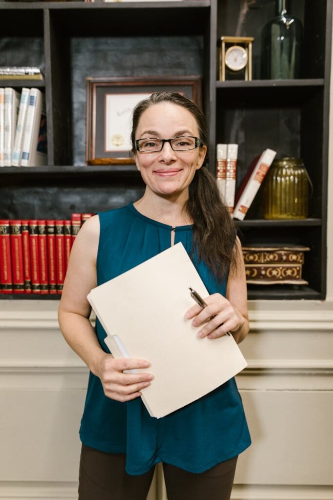 Confident woman standing in a law office holding documents with a warm smile.